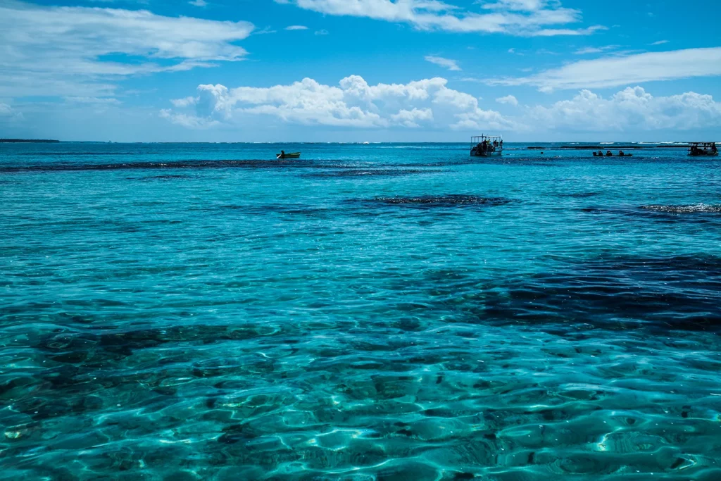 Vista paradisíaca das Praias de Maragogi, com a água azul cristalina e barcos ao fundo.