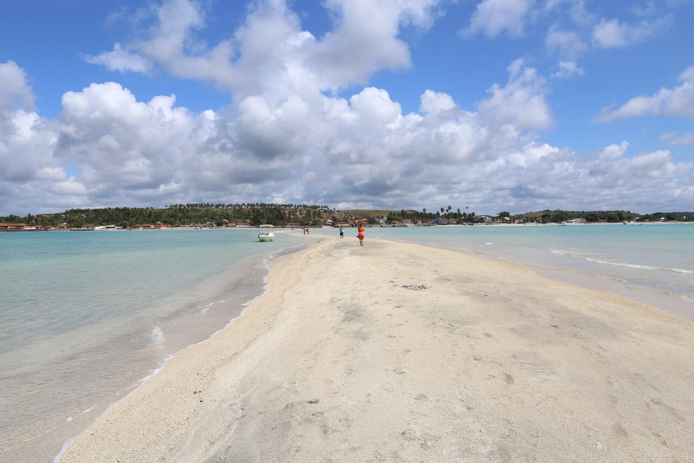 Vista da Praia de Barra Grande em Maragogi com um caminho de areia que cruza o mar na maré baixa.